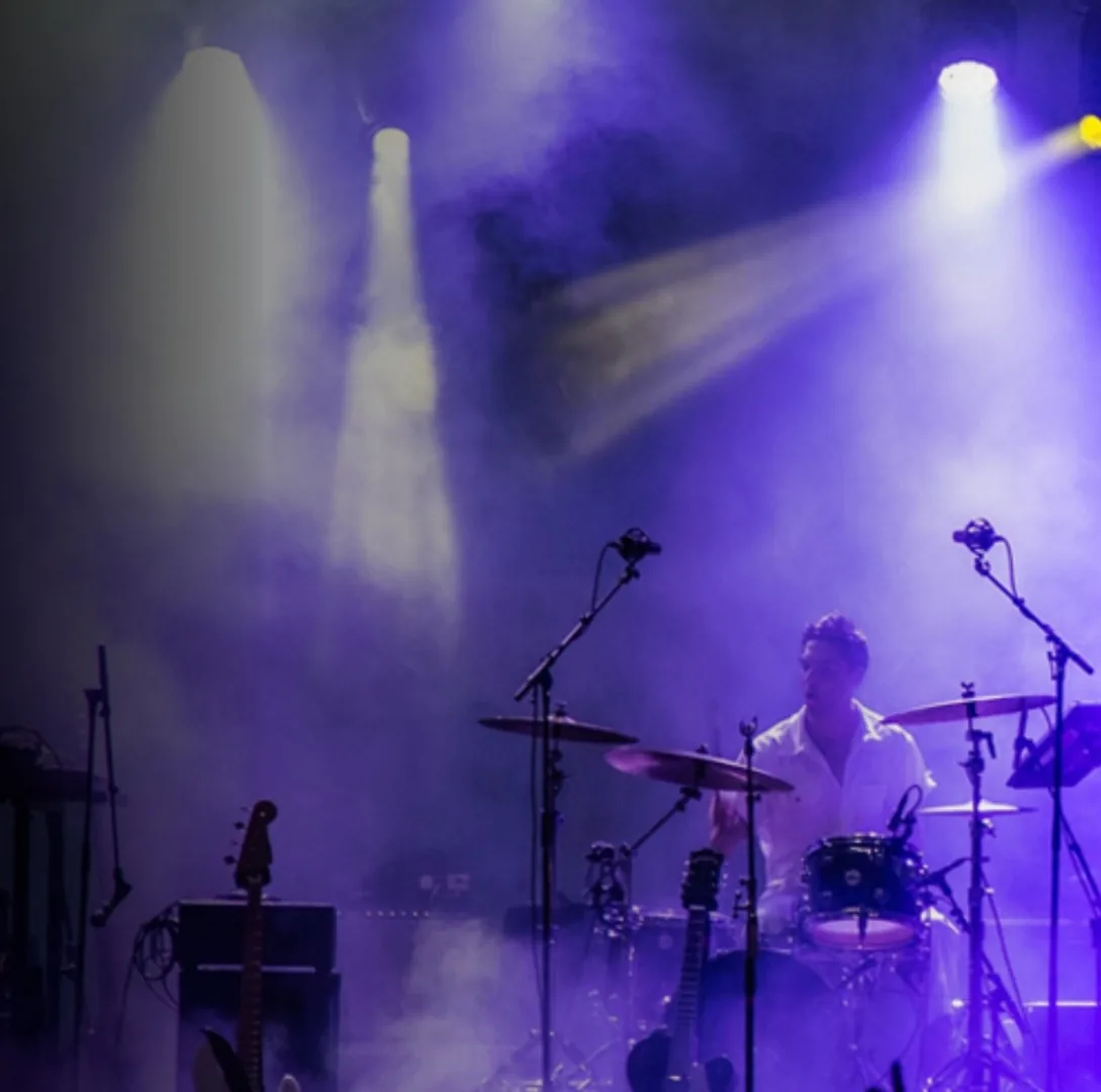 Moody stage wash lighting on a drummer during a live set